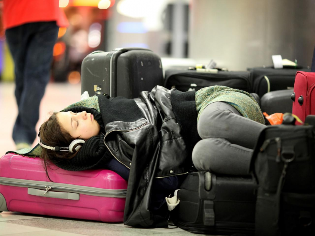 a girl sleeping in airport with luggage